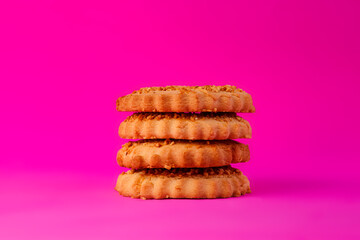 Shortbread cookies sprinkled with slices of hazelnut on a purple background. Delicious homemade cakes made from natural ingredients. Space for text.