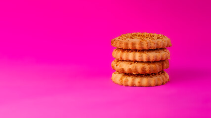 Shortbread cookies sprinkled with slices of hazelnut on a purple background. Delicious homemade cakes made from natural ingredients. Space for text. Wide format view.