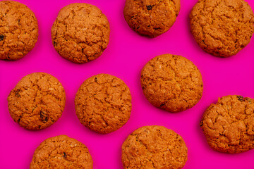 Oatmeal cookies with raisins and nuts inside on a purple background. Delicious homemade cakes made from natural ingredients. Top vew.