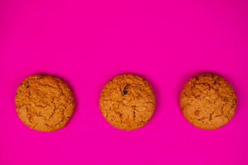 Oatmeal cookies with raisins and nuts inside on a purple background. Delicious homemade cakes made from natural ingredients. Space for text.
