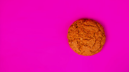 Obraz na płótnie Canvas Oatmeal cookies with raisins and nuts inside on a purple background. Delicious homemade cakes made from natural ingredients. Space for text. Wide format view.