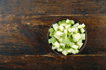 Sliced zucchini in a bowl on a wooden background. Vegetable, ingredient and staple food.