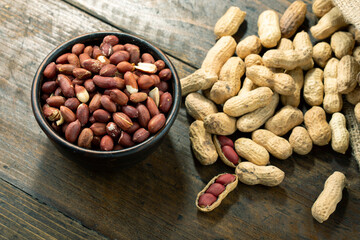 Peanuts in a clay plate on a wooden table. Inshell nuts.