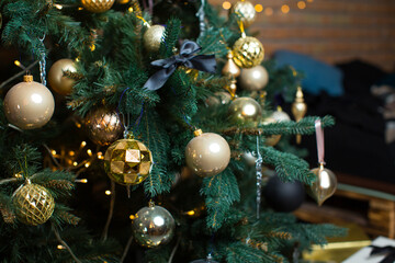 Obraz na płótnie Canvas Green beautiful Christmas tree decorated with gold and beige balls, garlands. Brick wall. Background for greeting card Happy New Year, Merry Christmas.