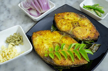 Closeup of two fired King Fish pieces with the ingredients to make a curry out of it.