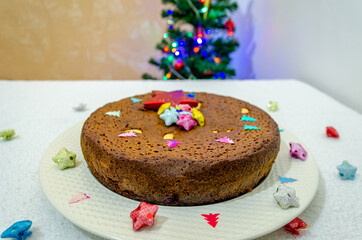 Christmas Special plum cake in a white plate with Christmas decorations and a Christmas tree in the background