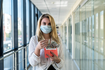 charming young lady in a medical mask holding an envelope with money in the mall