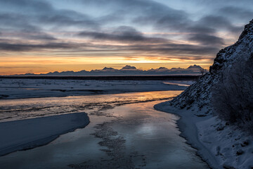 Beautiful reflection in Tanana river of sunset dramatic sky in winter. Alaska, USA
