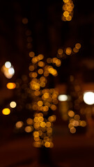 Abstract evening night shimmering bokeh background effect street outside near cafe restaurant. Defocused urban city life blur golden light bulbs garlands. Christmas New Year party holiday concept. 
