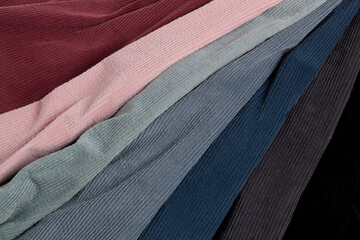 Multicolored fabrics folded in a stack . Multi-colored corduroy textile. Velvet. - obrazy, fototapety, plakaty