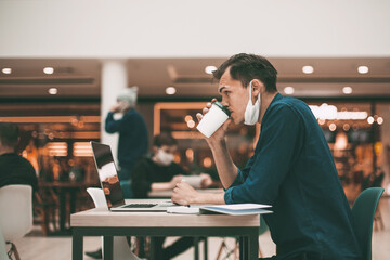side view. casual young man with coffee takeaway sitting at a cafe table