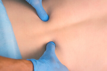 Man doctor physiotherapist acupuncturist in gloves is preparing woman to acupuncture massaging her...