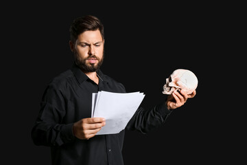Male actor with human skull on dark background