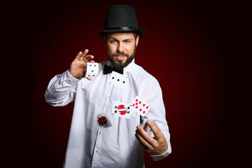 Male magician showing tricks with cards on dark background