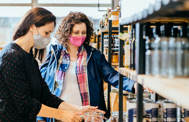 Salesperson in protective mask helps a pregnant woman at a wholesale food store. The seller advises...