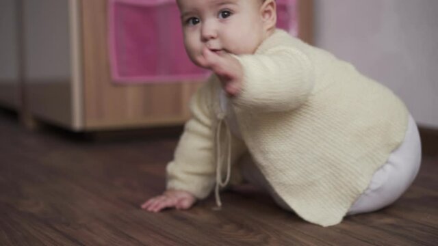 infant, childhood concept - happy funny playfull toddler kid 8 month baby girl learn to sit singly play in playroom. smiling chubby active awake newborn in white crawl on knees floor indoors at home