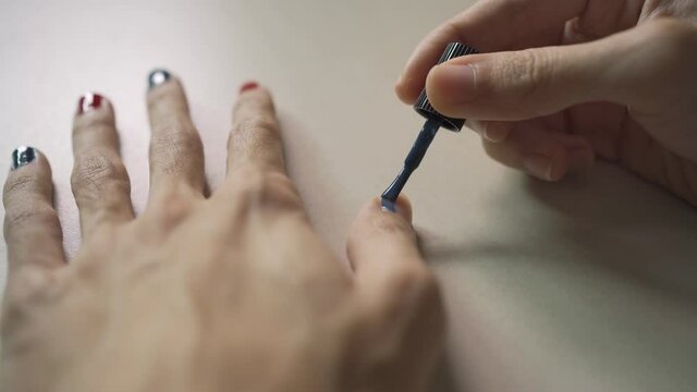 A man painting his own fingernails with nail polish