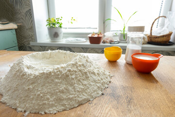 Preparation of dough, flour, eggs and wooden rolling pin on gray background.