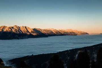Nebel im Tal, Berge in den Alpen leuchten