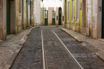 Fototapeta na wymiar Empty narrow cobblestone street or alley with tramway rails, Lisbon, Portugal