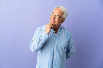 Middle age Brazilian man isolated on purple background looking up while smiling