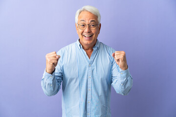 Middle age Brazilian man isolated on purple background celebrating a victory in winner position