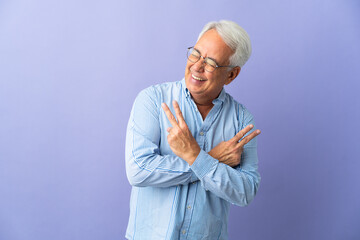 Middle age Brazilian man isolated on purple background smiling and showing victory sign
