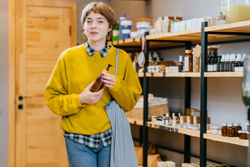 Woman with cotton bag buying personal hygiene items in zero waste shop. Eco Organic Cosmetics. Girl choose toiletries products in plastic free store. Minimalist lifestyle. Shopping at local businesses