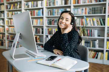 Remote work. Happy young pretty woman, call center worker, teacher or manager, wearing  a headset,...
