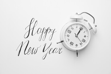Alarm clock with text HAPPY NEW YEAR on white background