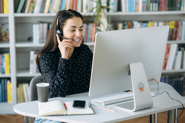 Caucasian cheerful young woman, call center worker, teacher or manager, wearing  a headset, looks...