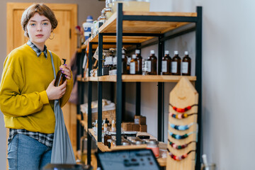 Woman with cotton bag buying personal hygiene items in zero waste shop. Eco Organic Cosmetics. Girl choose toiletries products in plastic free store. Minimalist lifestyle. Shopping at local businesses