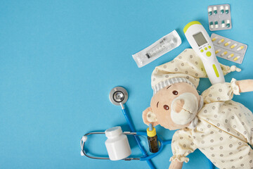 cute teddy bear, medication. stethoscope and non-contact infrared thermometer on blue background