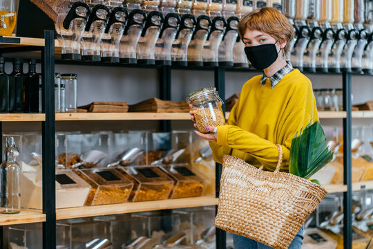 Shopping, Food, Sale, Consumerism Concept. Blond Shot Haired Woman In Face Protective Mask For Protection From Virus Disease Buying At Grocery Store Reusable Eco Bag For Shopping. Zero Waste Concept.