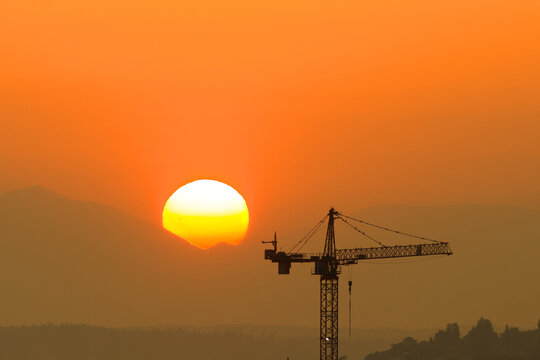 Construction tower against a setting sun.