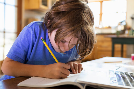 Young boy at home writing and drawing in his drawing pad