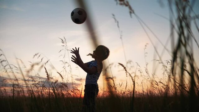 Childhood dream. boy play soccer ball in the park silhouette. happy family fun kid dream concept. kid boy play on the field silhouette at sunset carries a soccer ball. baby winner