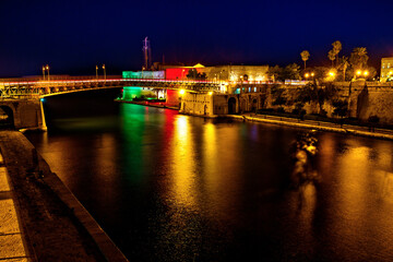 Fototapeta premium The revolving steel bridge of Taranto, Puglia, Italy, on the water channel, seen illuminated at night, long exposure photo