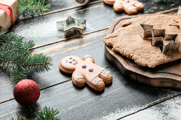 Christmas composition with gingerbread cookie and fresh dough on dark wooden background