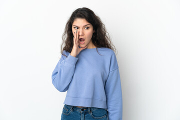 Teenager Russian girl isolated on white background whispering something with surprise gesture while looking to the side