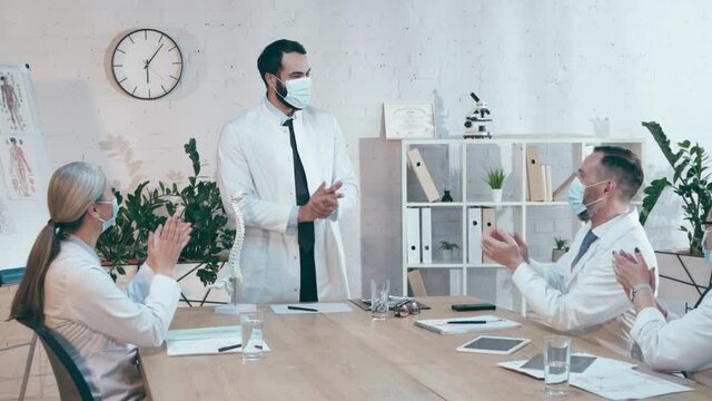 multicultural doctors in medical masks applauding during medical conference