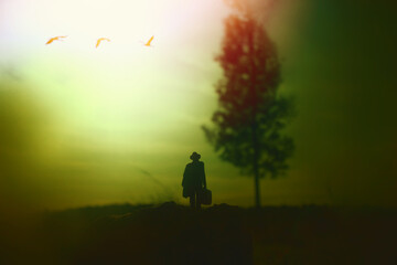 Surreal image of mysterious man walking alone in field during sunset