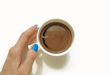 White cup of coffee and female hand with a blue manicure isolated on a white background. Top view