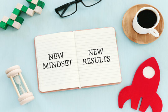 top view image of table with open notebook and the text new mindset new results. success and personal development concept
