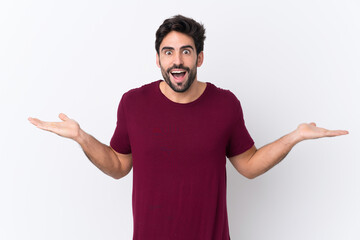 Young handsome man with beard over isolated white background with shocked facial expression