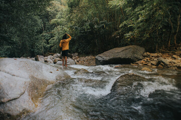 Male traveler explore the beautiful of rainforest stream in the morning.Male traveler camping in the rainforest.Grain effects and tone color applied.