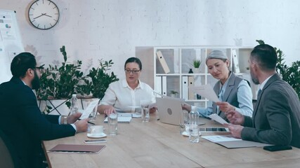 multicultural businesspeople talking and working with documents during meeting