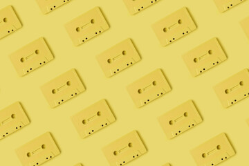 Pattern made with retro audio cassettes on modern yellow background. Creative concept of retro technology. 70's or 80's aesthetic. Flat lay, top view.