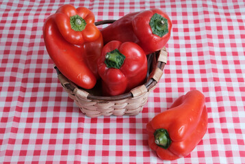 Red peppers in a traditional basket. Red and white cloth. Italian fabric. Ingredients. Fresh vegetables. Vitamin.