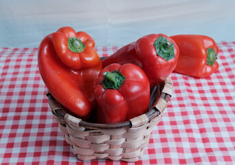 Red peppers in a traditional basket. Red and white cloth. Italian fabric. Ingredients. Fresh vegetables. Vitamin.